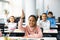 Diverse small schoolkids raising hands at classroom