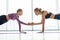 Diverse sportive female yogi stand on rubber mat giving high five in side plank position. Young girls in sportswear practice yoga