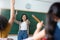 Diverse Student raising their hands up in classroom at international elementary school