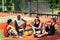Diverse team of basketball players getting some rest after game at outdoor court, blank space