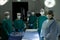 Diverse team of surgeons and techs ready for operation, standing around operating table in theatre