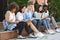 Diverse teen friends studying together in university courtyard, preparing for exams