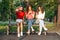 Diverse three girl friends using their phones outdoors. Group gen z young people using mobile smartphone sitting on