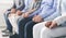 Diverse Unrecognizable People Holding Hands, Sitting In A Row Indoors