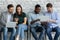 Diverse young people browsing gadgets preparing for interview in office