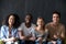 Diverse young people sitting holding phones looking at camera