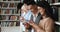 Diverse young people stand in line at library using phones