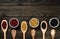 Diversity of beans inside wooden spoons. Black wood background