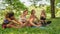 Diversity female friends relaxing on grass lawn in park after having workout together