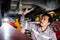 Diversity mechanic teamwork, a Japanese mechanic repairman in a grey uniform inspects the car bottom problems of a lifted car.