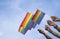 Diversity people hands raising colorful lgbtq rainbow flags together, background blue sky