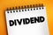 Dividend - distribution of profits by a corporation to its shareholders, text concept on notepad