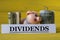 DIVIDENDS - word on a white strip of paper on a piggy bank pig on a yellow background with banknotes