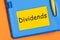 Dividends the word is written in black letters on the yellow paper for notes