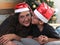 Divorced single mom and 7-year-old dark-skinned Latino son wear Santa hats in front of the Christmas tree to celebrate in solitude