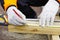 diy Carpenter marks a piece of wood. carpenter& x27;s hands in white gloves and tools for precise work