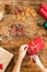 DIY Gift Wrapping. Woman wrapping beautiful red christmas gifts on rustic wooden table. Overhead point of view of christmas