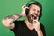 Dj with beard wears headphones. Man sings on green background. Singer with beard and excited face listens to music.