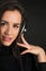 DJ girl in earphones listening disco beats posing in studio over dark background. Young attractive Caucasian woman model