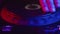 DJ's hand adjusts rotating jog on digital music console in neon light in nightclub, closeup. Concept of professional