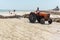 DJERBA, TUNISIA, JULY 18, 2016: Tractor worker cleans algae and debris from the beach