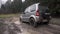 Dmitrov, Russia - CIRCA 2020: Gray Suzuki Jimny suv slowly drives through deep puddle. splash flying. back view. offroad