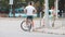 DNIPRO, UKRAINE - July 3, 2019: The guy with bicycle at the crossroads of the street with heavy traffic. A man waiting for a green