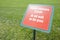 Do not walk on the grass - concept image white text on signboard and fresh green lawn - text in English and Italian