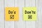 Do`s and Don`ts on two sticky notes  on weathered whitewash textured wood