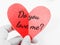 Do you love me, text on red heart paper. A hand holding a red heart shape of paper with text