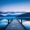dock on lake with mountains in the background at dusk with fog on the water