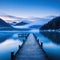 dock on lake with mountains in the background at dusk with fog on the water