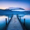 dock on lake with mountains in the background at dusk with fog on the water