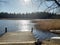 Dock on a lake. Peacful sunny day.  Calm lake and sun. Wind blowes on the sunny lake. Forest and lake. Alone. Calmness.