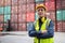 Dock manager or engineer worker in safety vest standing in shipping container yard crossed arm with smile. Import and export