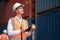 Dock manager or engineer worker in safety vest standing in shipping container yard holding tablet with smile. Import and export