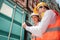 Dock manager woman and engineer worker looking at tablet and check stock in shipping container yard with smile. Import and export