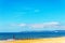 Dock pilings on a sandy beach, blue ocean and yellow sand, sunny