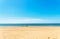 Dock pilings on a sandy beach, blue ocean and yellow sand, sunny