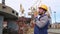 Dock worker with yellow helmet and walkie-talkie directs the cargo crane in Shipping port