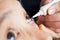 Doctor apply artificial tears gel to senior woman patient eye