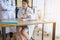Doctor beautiful asian woman sitting and working on desk using foot fingers plastic anatomy physiology model a bone and hand point