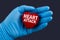 Doctor in blue gloves holds a heart with text Heart Attack, concept