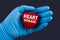 Doctor in blue gloves holds a heart with text Heart Disease, concept