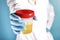 Doctor in blue gloves holds plastic test jar with yellow urine in his hand. analysis concept