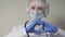 A doctor in a blue mask and gloves smiles and shows his heart, a professional cardiologist in a health clinic, an