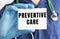 A doctor in a blue medical suit holds a card with the text PREVENTIVE CARE. Medical concept.