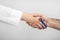 Doctor with blue ribbon on finger and patient holding hands against grey background. Symbol of medical issues