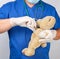 doctor in blue uniform bandages white medical bandage paw brown teddy bear