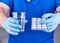 Doctor in blue uniform holds a glass of water and a pack of white pills